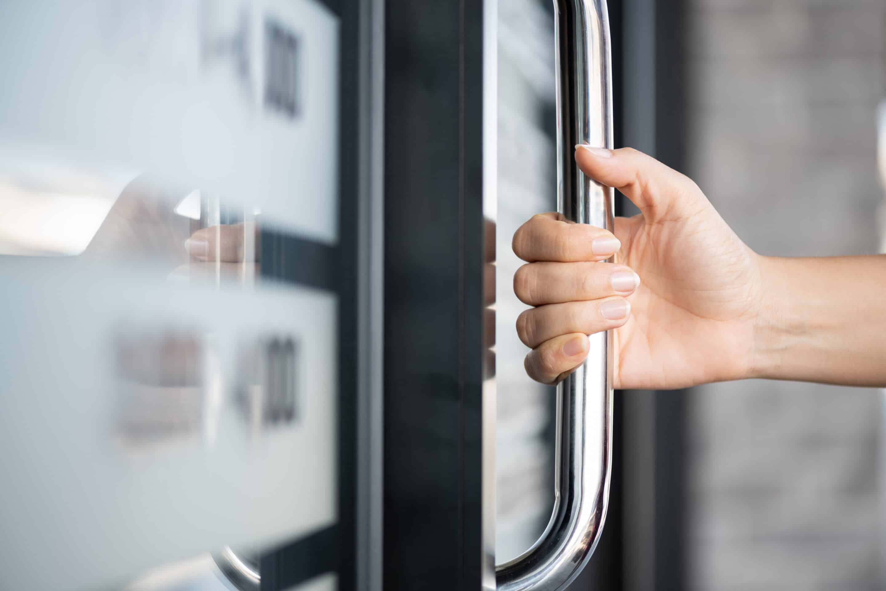 Closeup woman hand holding a door that is fail safe Closeup woman hand holding a door that is fail safe